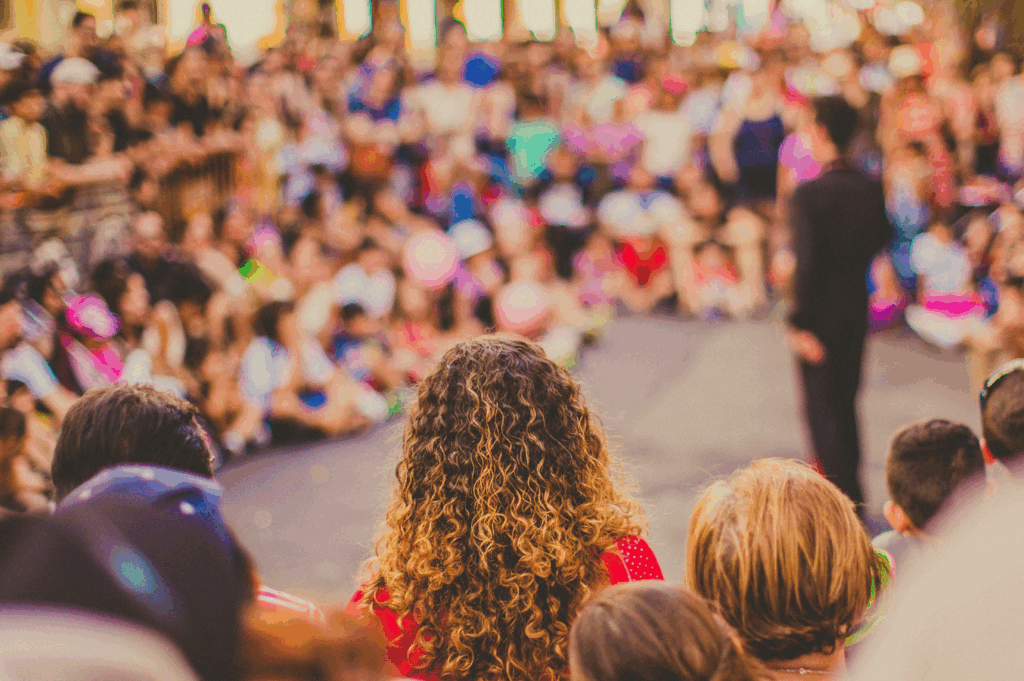 Photo of people watching a live performance with a speaker standing in the middle.